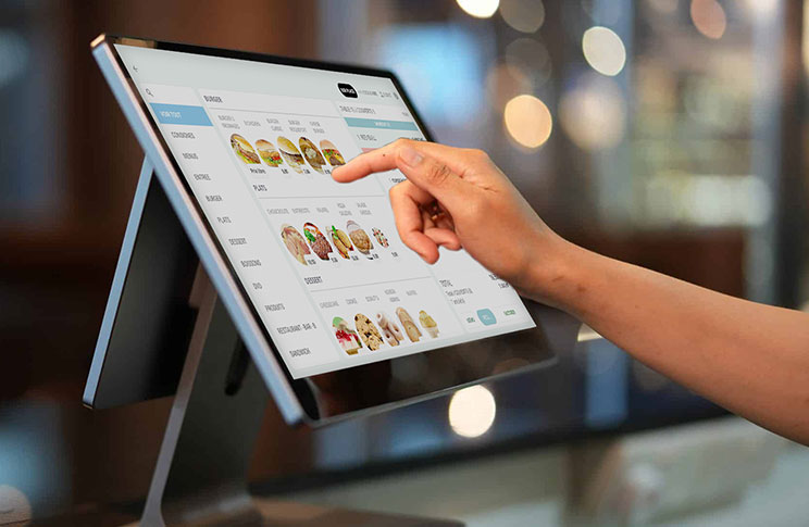 Caisse enregistreuse tactile moderne avec interface intuitive, utilisée par un serveur dans un restaurant suisse.